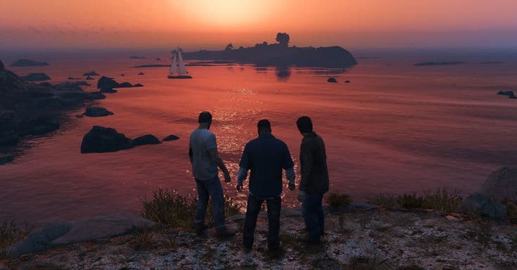 Three people standing on a clifftop watching the sun set over the ocean, a sailing boat anchored near a small island.