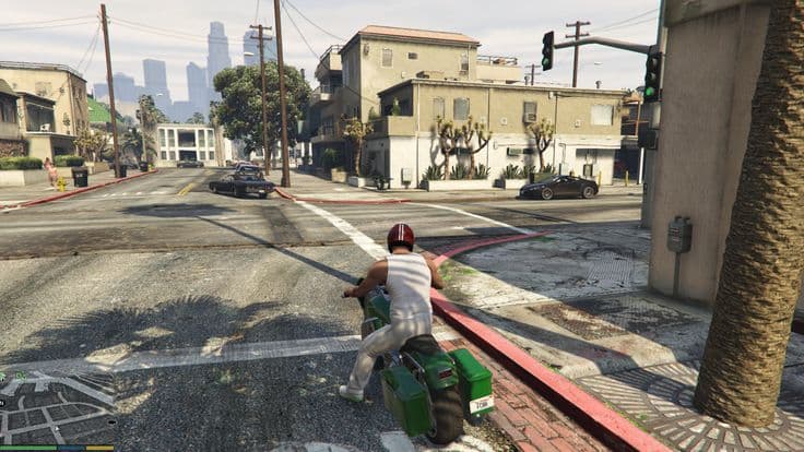 A rider on a motorcycle crossing an empty intersection on a wide suburban street, the downtown skyline hazy in the distance.